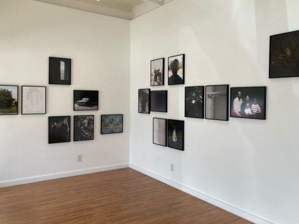 Art gallery filled with medium-sized photographs hung according to a grid pattern, with several cells left empty.