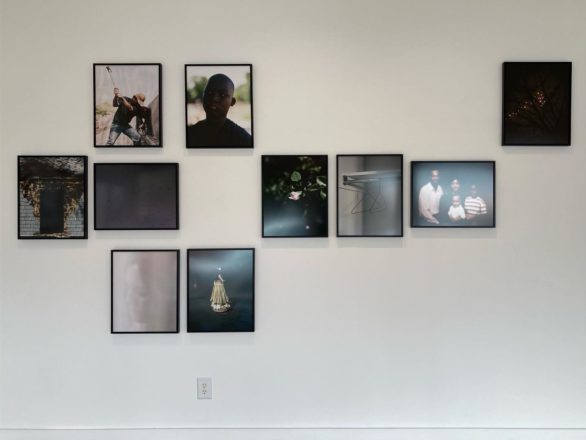 An art gallery wall with medium-sized photographs hung according to a grid pattern, with several cells left empty.