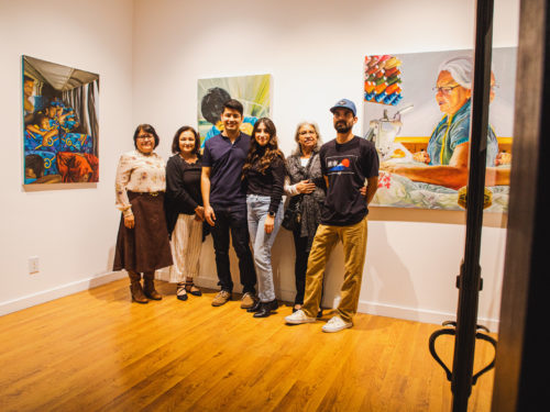 Six members of a family pose for a photograph, standing in an art gallery surrounded by paintings.