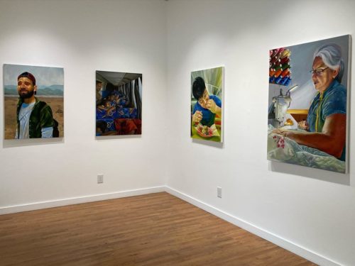 An art gallery with four medium-sized paintings hanging on the walls.