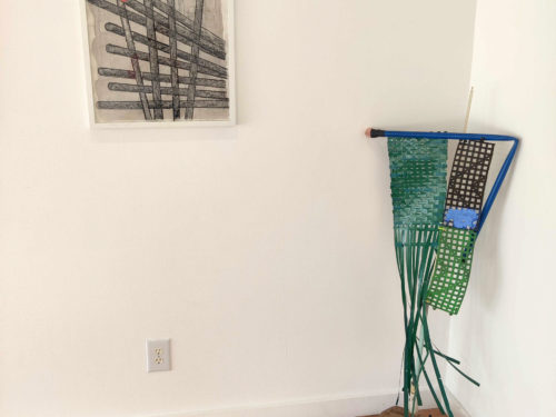 Artwork on display in a gallery: A drawing of shuttlecocks; a sculpture made of an old vacuum cleaner.